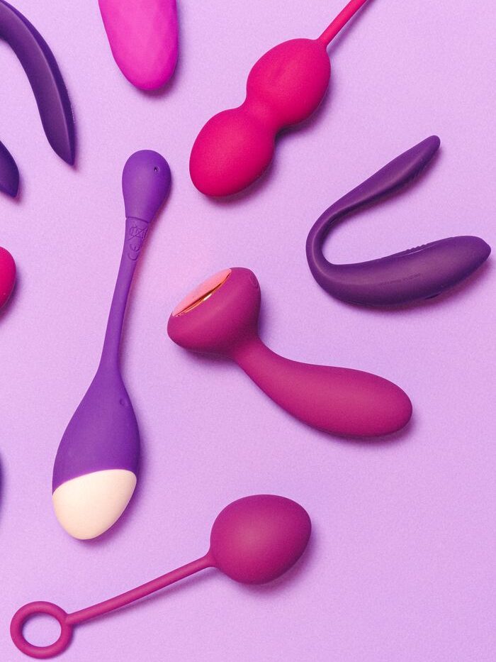 A variety of colorful silicone sex toys on a purple background showcasing modern pleasure products.